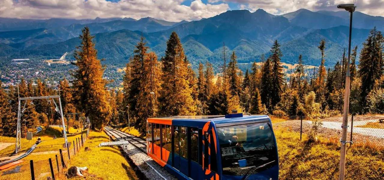 Kolejka linowa wjeżdża na górę, oferując widok na jesienne Zakopane i Tatry. To jedna z głównych atrakcji regionu.
