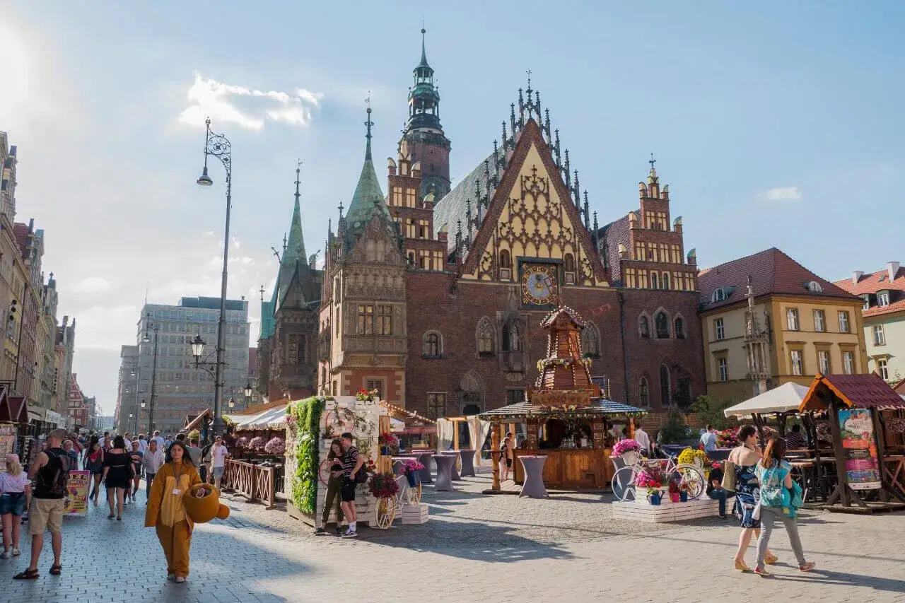 Wrocławski Rynek podczas wycieczki do Wrocławia 3 dni. Ludzie spacerują wśród kramów i zabytkowej architektury.