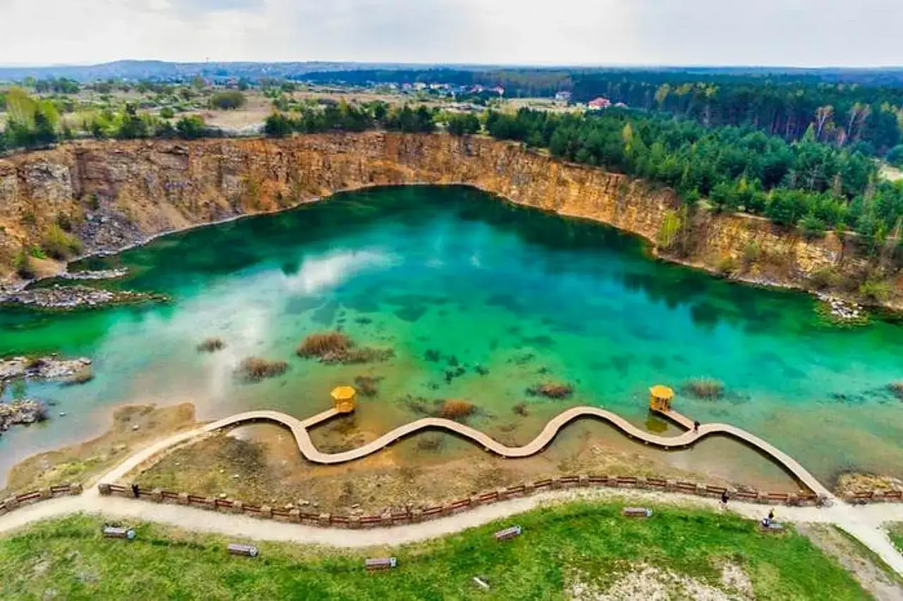 Malowniczy park Gródek z turkusową wodą w kamieniołomie, drewnianą kładką i otaczającym lasem.