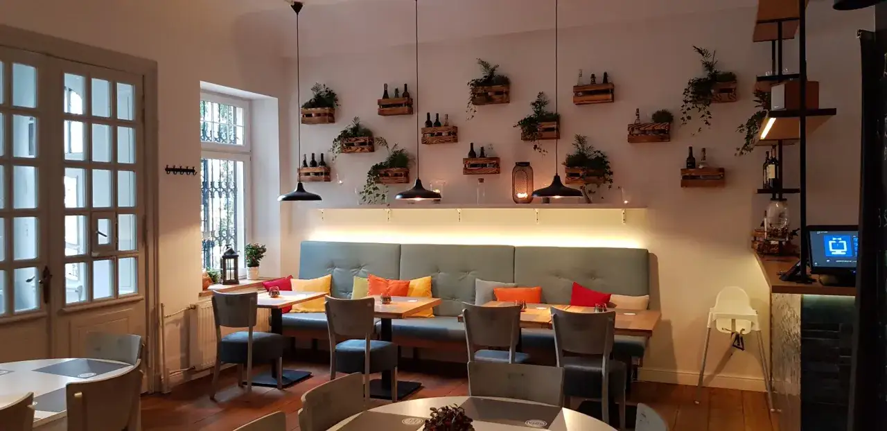 Przytulne wnętrze restauracji Nova Sopot z wygodnymi kanapami, drewnianymi skrzynkami na ścianach i stylowymi lampami.