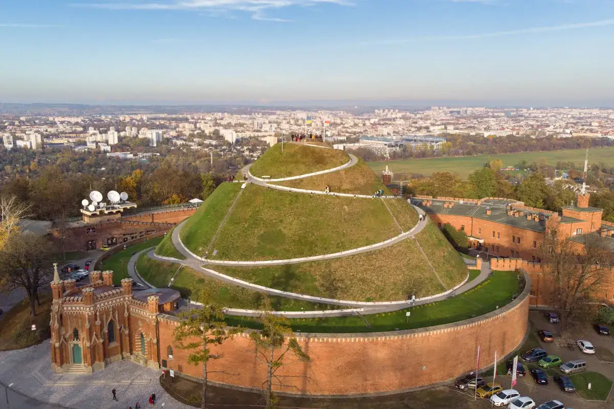 Kopiec Kościuszki, jeden z krakowskich top attractions, z widokiem na miasto. Kręta ścieżka prowadzi na szczyt zielonej kopuły.