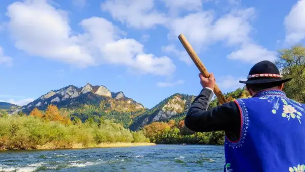 Flisacy Dunajec w tradycyjnych strojach płyną tratwą przez malowniczy przełom rzeki. Góry Pieniny jesienią zachwycają kolorami.