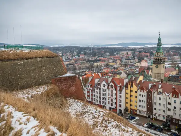 Zimowy krajobraz miasta na Dolnym Śląsku, z widokiem na kolorowe kamienice i wieżę ratuszową. Idealne miejsce na ferie zimowe.