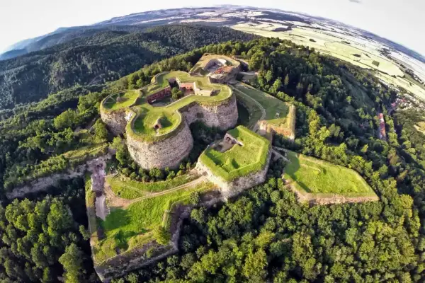 Twierdza na wzgórzu, z której można zejść do podziemnych tras turystycznych. Otoczona lasem, z widokiem na pola i miasteczko.