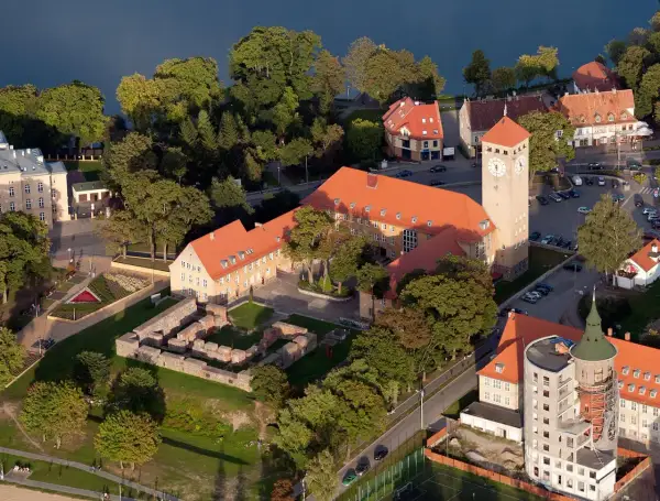 Szczytna atrakcje: ruiny zamku, wieża zegarowa i budynki nad jeziorem.
