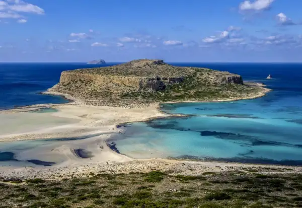 Malownicza zatoka z turkusową wodą i piaszczystą plażą, otoczona skalistymi klifami. To raj dla miłośników przyrody, ukazujący walory przyrodnicze Grecji.