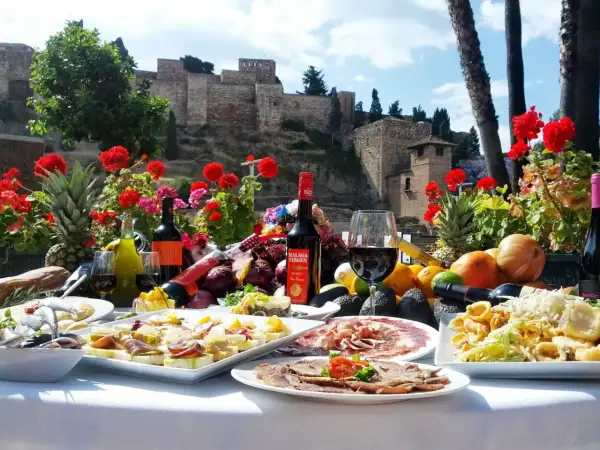 Uczta w jednej z malaga restauracji: tapas, wino i owoce na tle Alcazaby.
