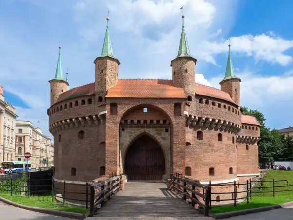 Barbakan w Krakowie, jedna z głównych kraków atrakcje, zaprasza do zwiedzania. Drewniany most prowadzi do zabytkowej budowli.