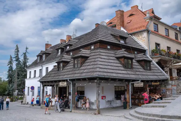 Kazimierz Dolny atrakcje: urokliwy rynek z kamieniczkami, lodziarnią i sklepikami. Ludzie spacerują, ciesząc się atmosferą.